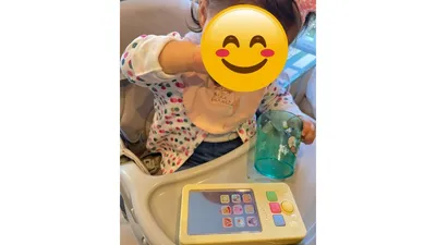 ハイチェアに座り、コップに手を伸ばす娘