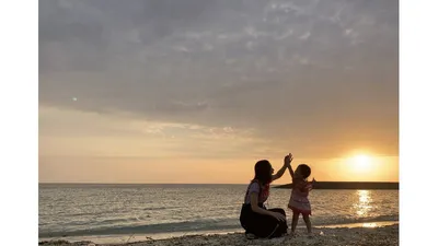夕暮れの海辺で、親子がハイタッチを交わすひとコマ