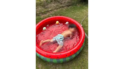 ビニールプールに入り、水の感触を全身で楽しむ子ども