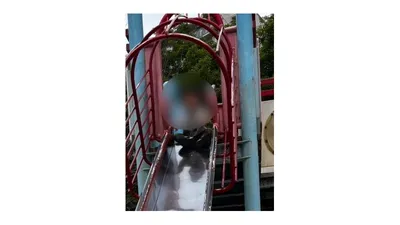 すべり台のてっぺんから、今まさに滑りおりようとする子ども