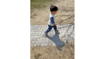 公園の石畳の上を、足元の感触を確かめながら歩く子ども