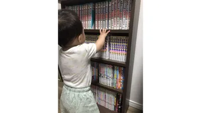 リビングの本棚に手を伸ばす1歳の息子